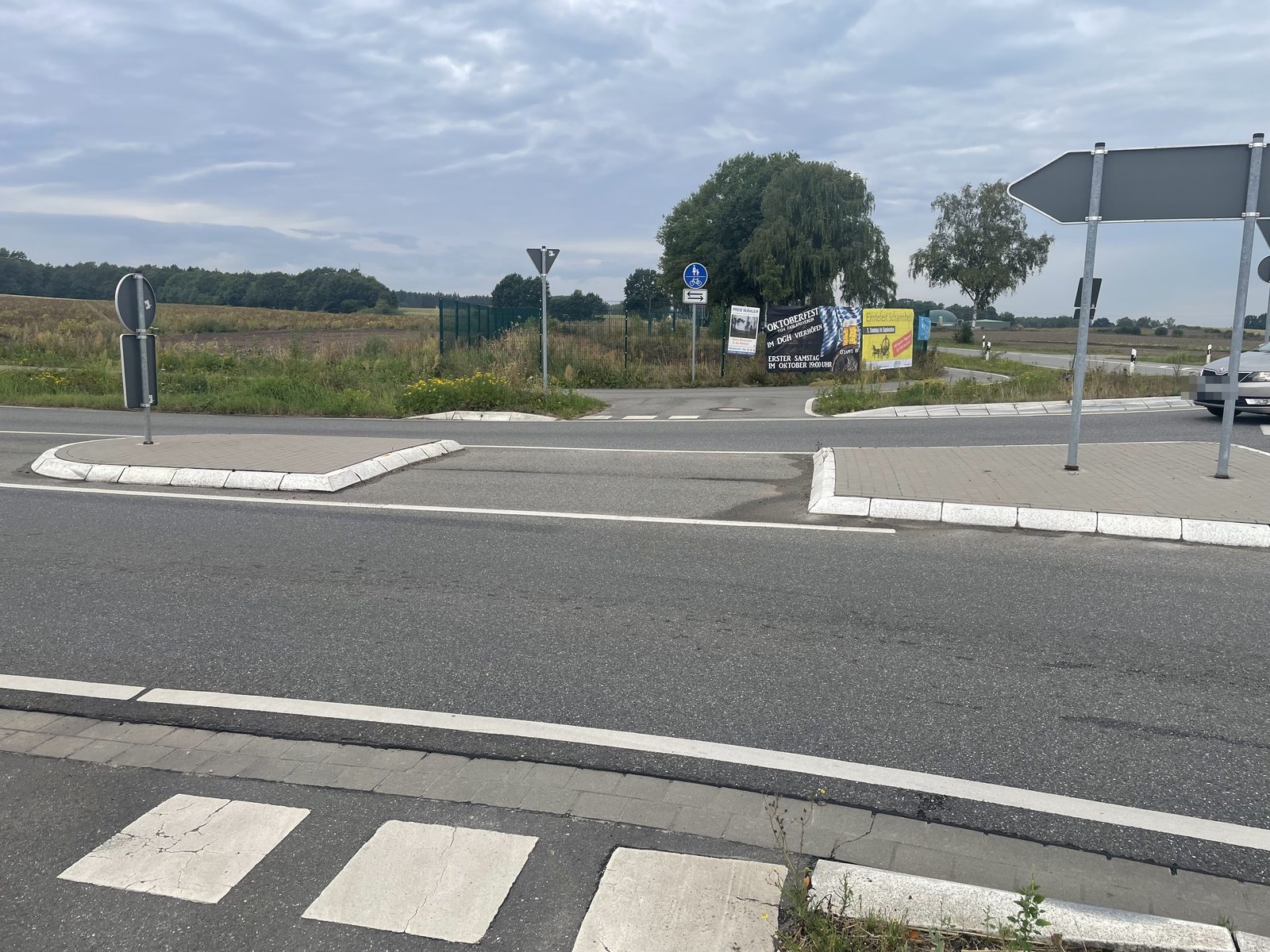 Die gebaute Querung am Bahlburger Kreisel: zwei erh&ouml;hte Inseln mit Bordstein und einer L&uuml;cke in der Mitte, ohne Markierung auf der Fahrbahn.